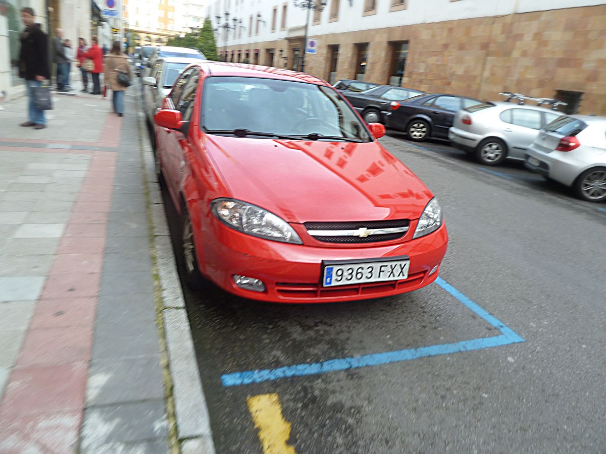 Red compact hatchback front view with sleek headlights and grille
