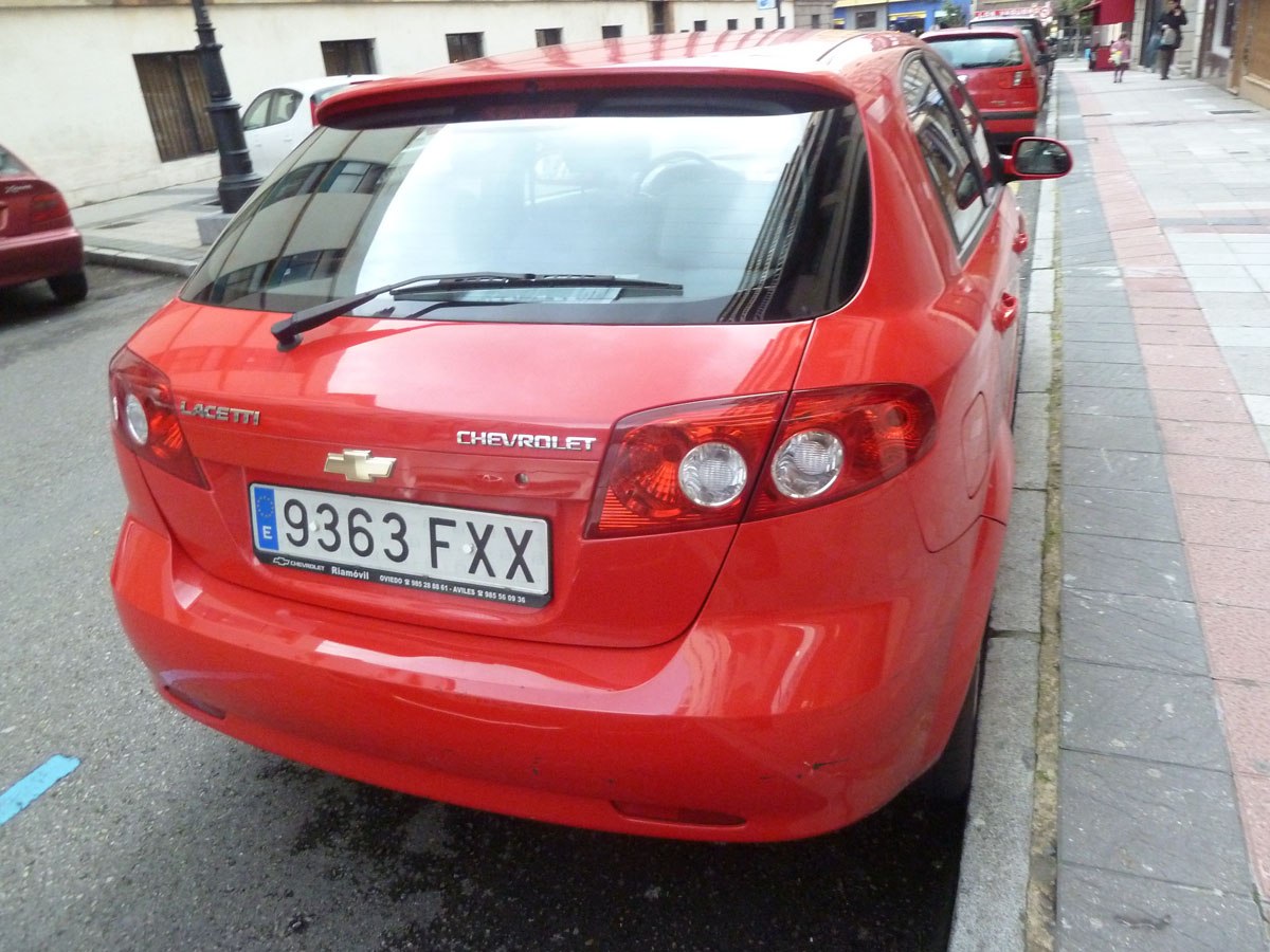 Rear view of red hatchback with distinct tail lights and rear wiper.
