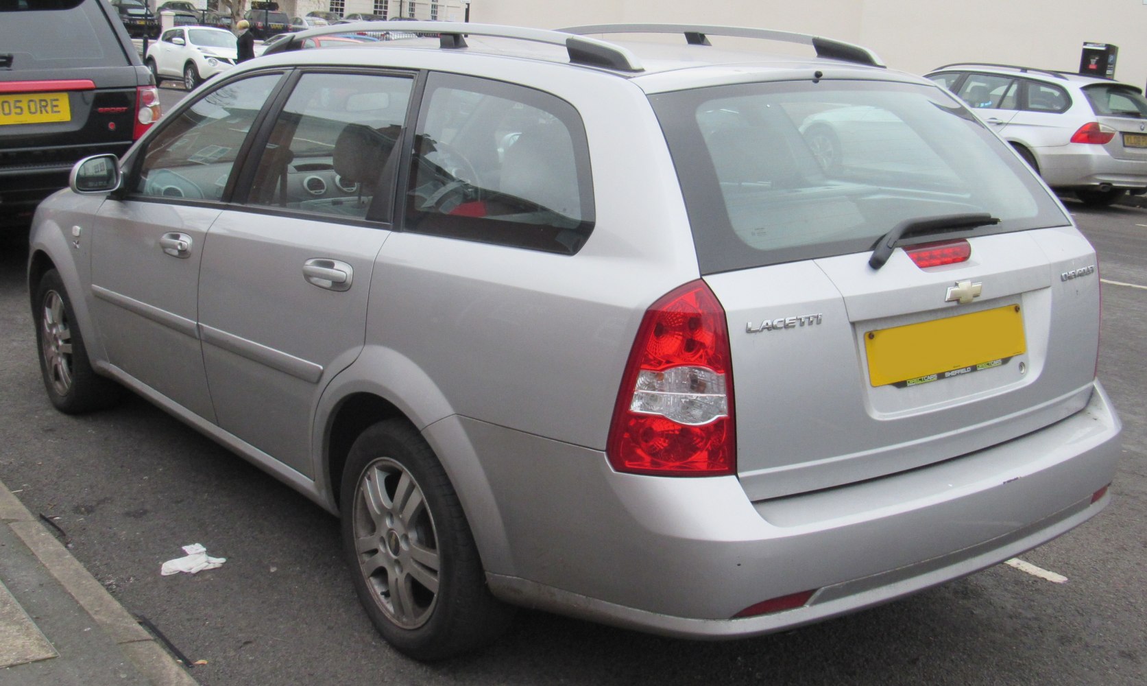 Rear side view of a silver estate car with roof rails and distinct taillights
