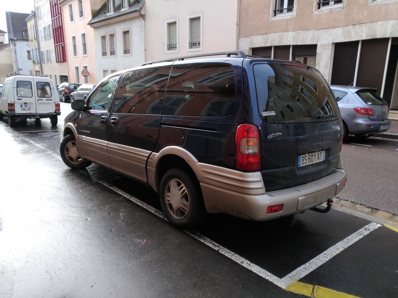 Rear-side view of two-tone Chevrolet minivan with large rear glass.