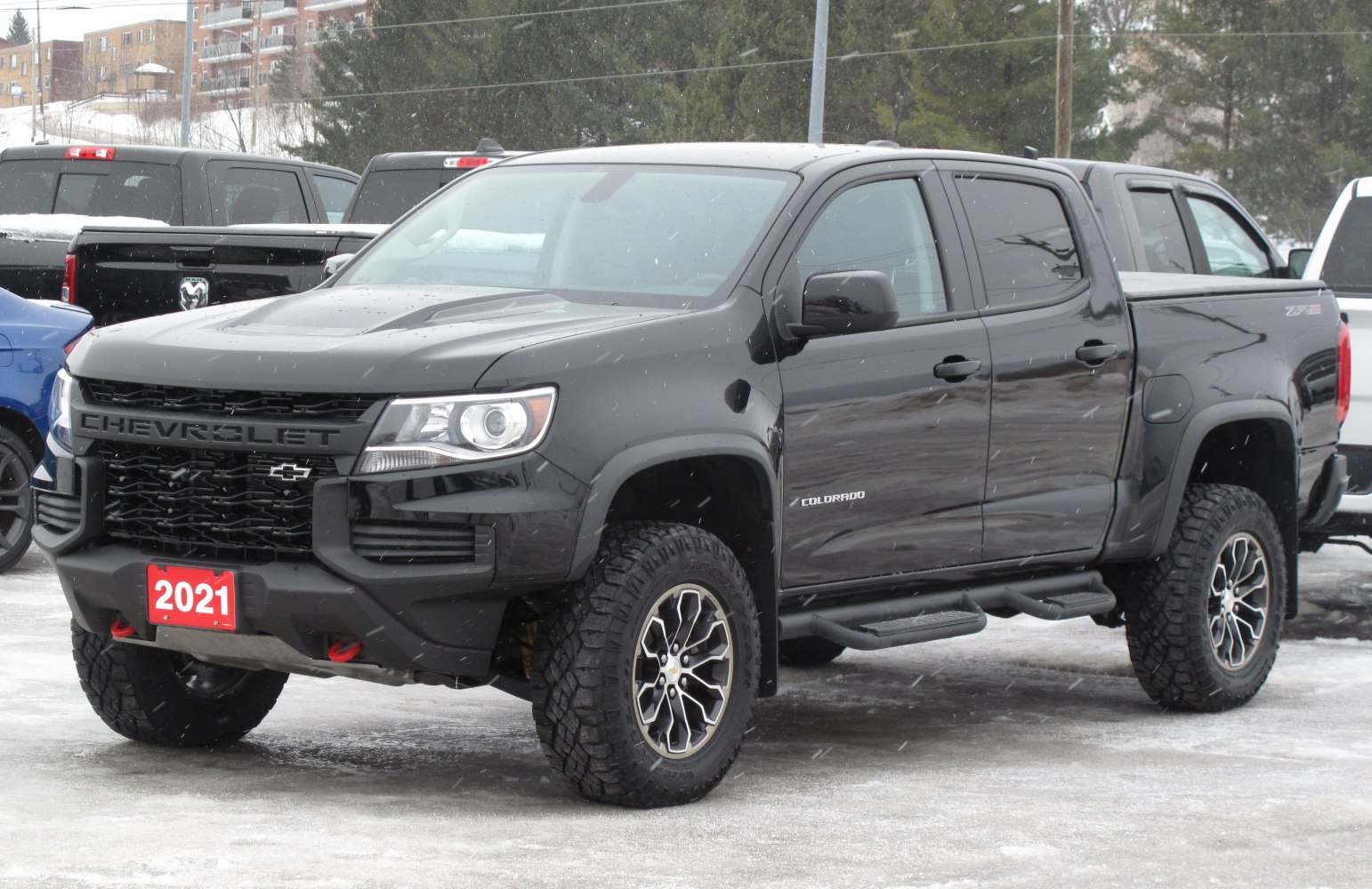 Black crew cab short box pickup with off-road tires and rugged features