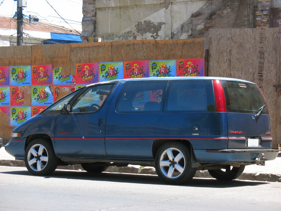 Side view of a vintage boxy minivan with large windows and distinctive rear lights