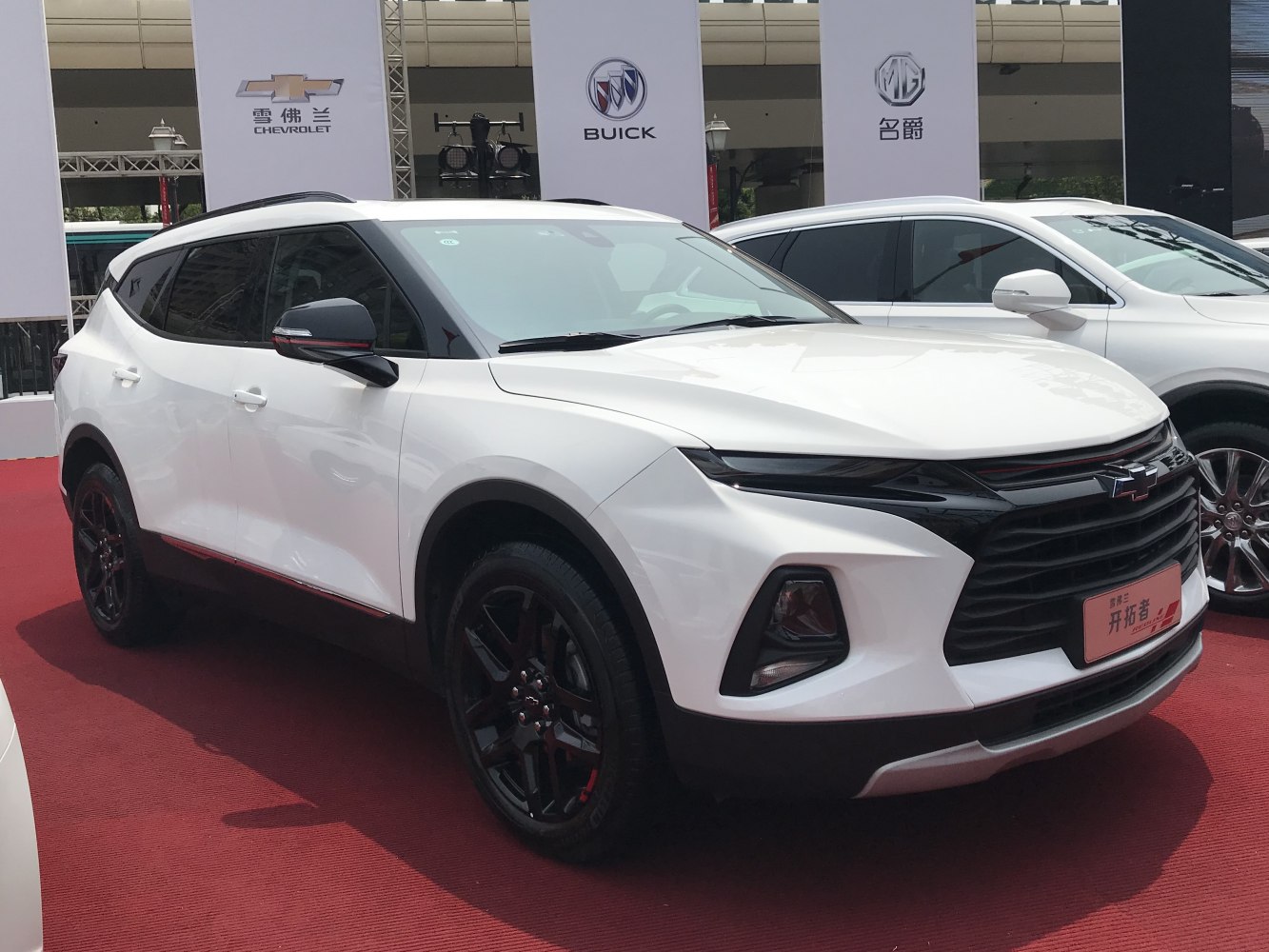 White mid-size SUV with black wheels, red accents, and sleek sporty front grille