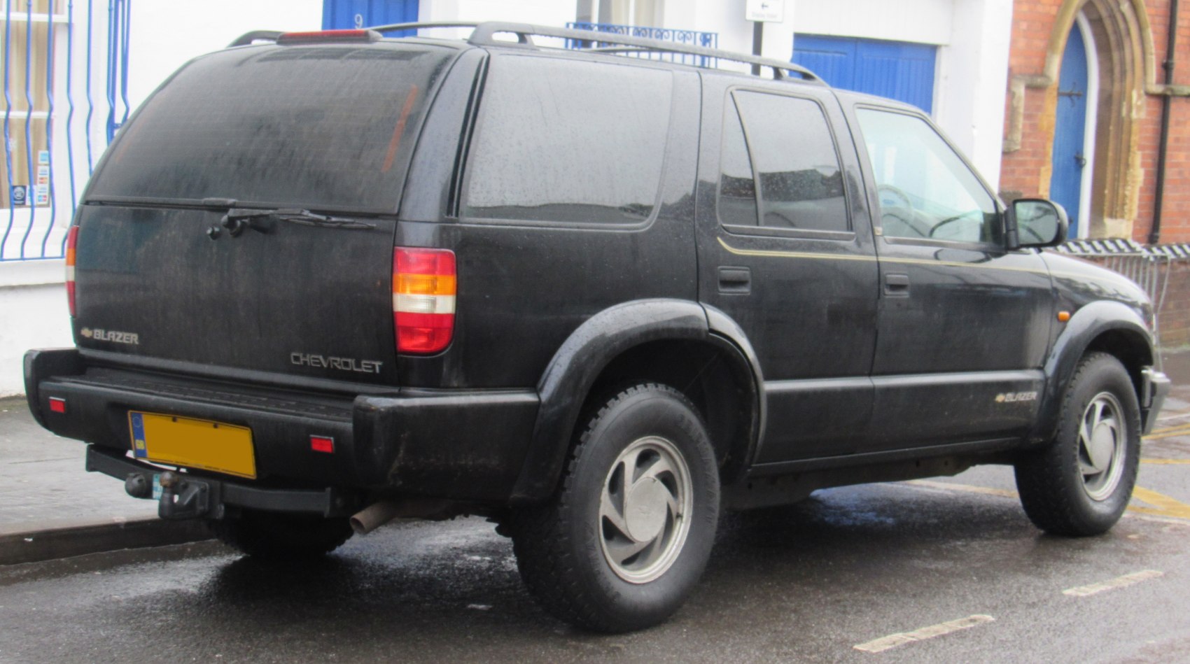 Black 4-door SUV rear side with off-road tires and tinted windows