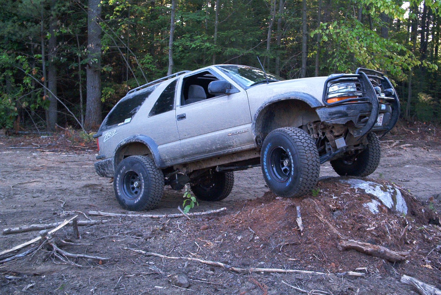 Lifted 2-door SUV with big all-terrain tires climbing over rough terrain