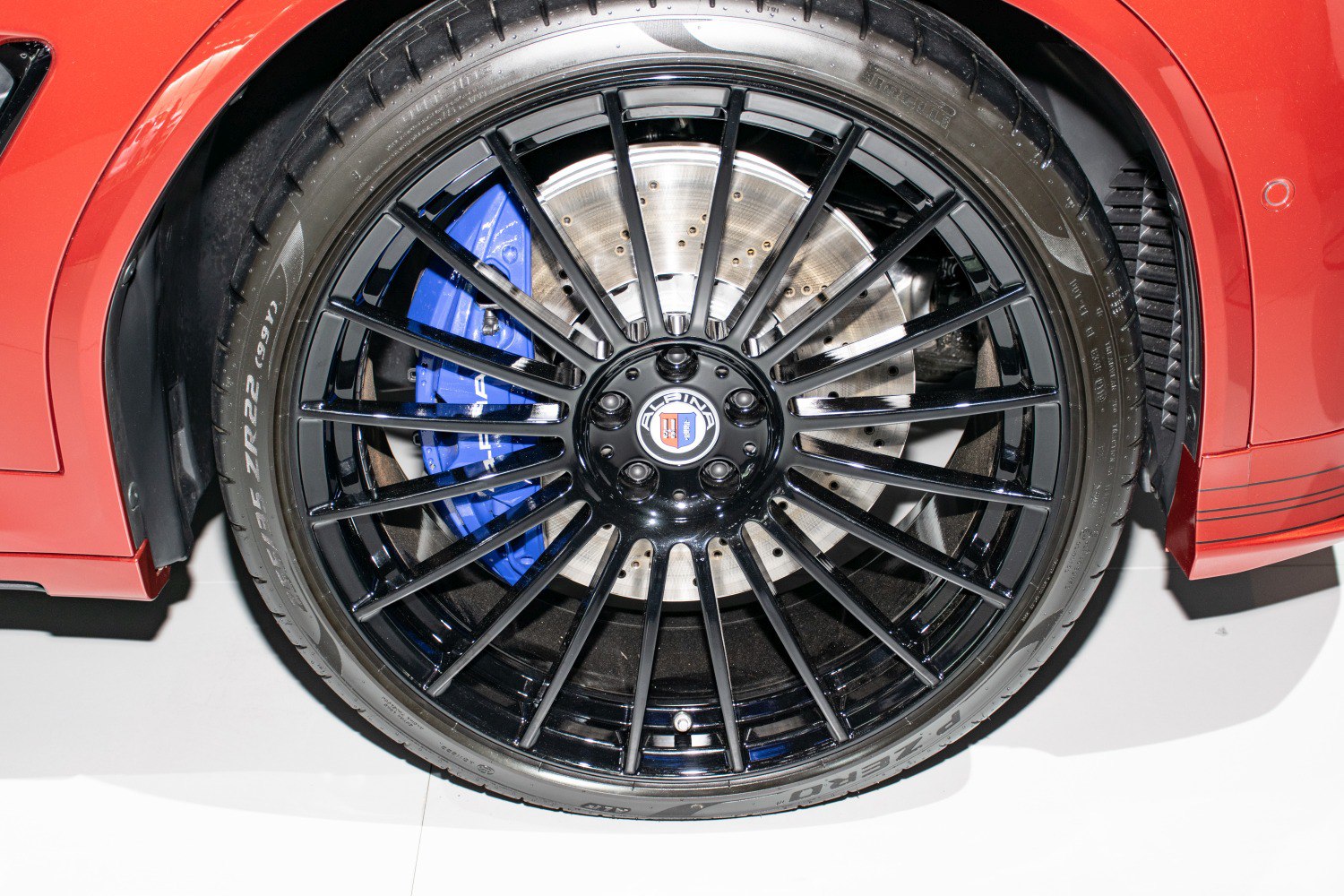 Black multi-spoke wheel with blue brake caliper and drilled brake disc