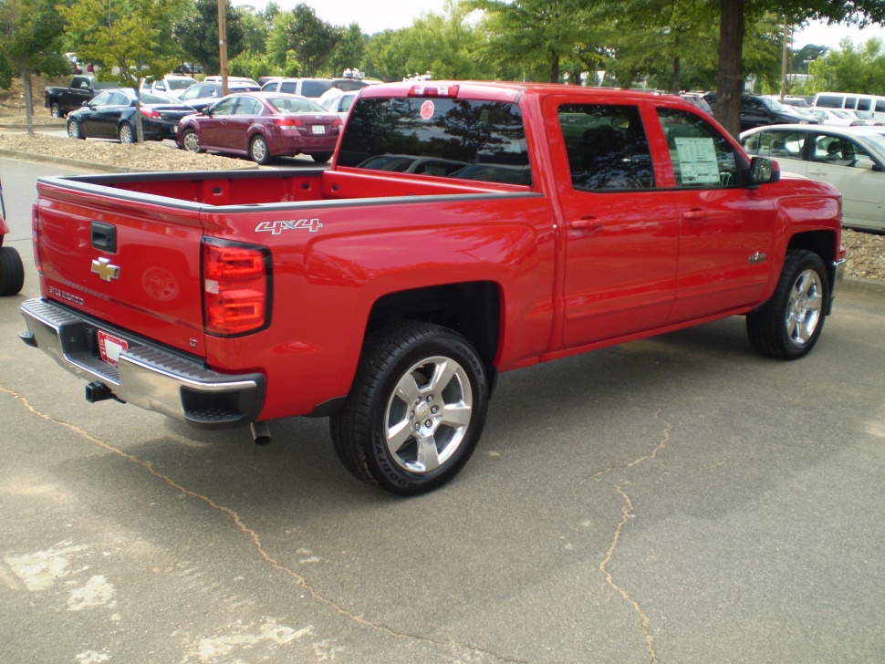 Red 4x4 pickup with crew cab and alloy wheels, rear and side view