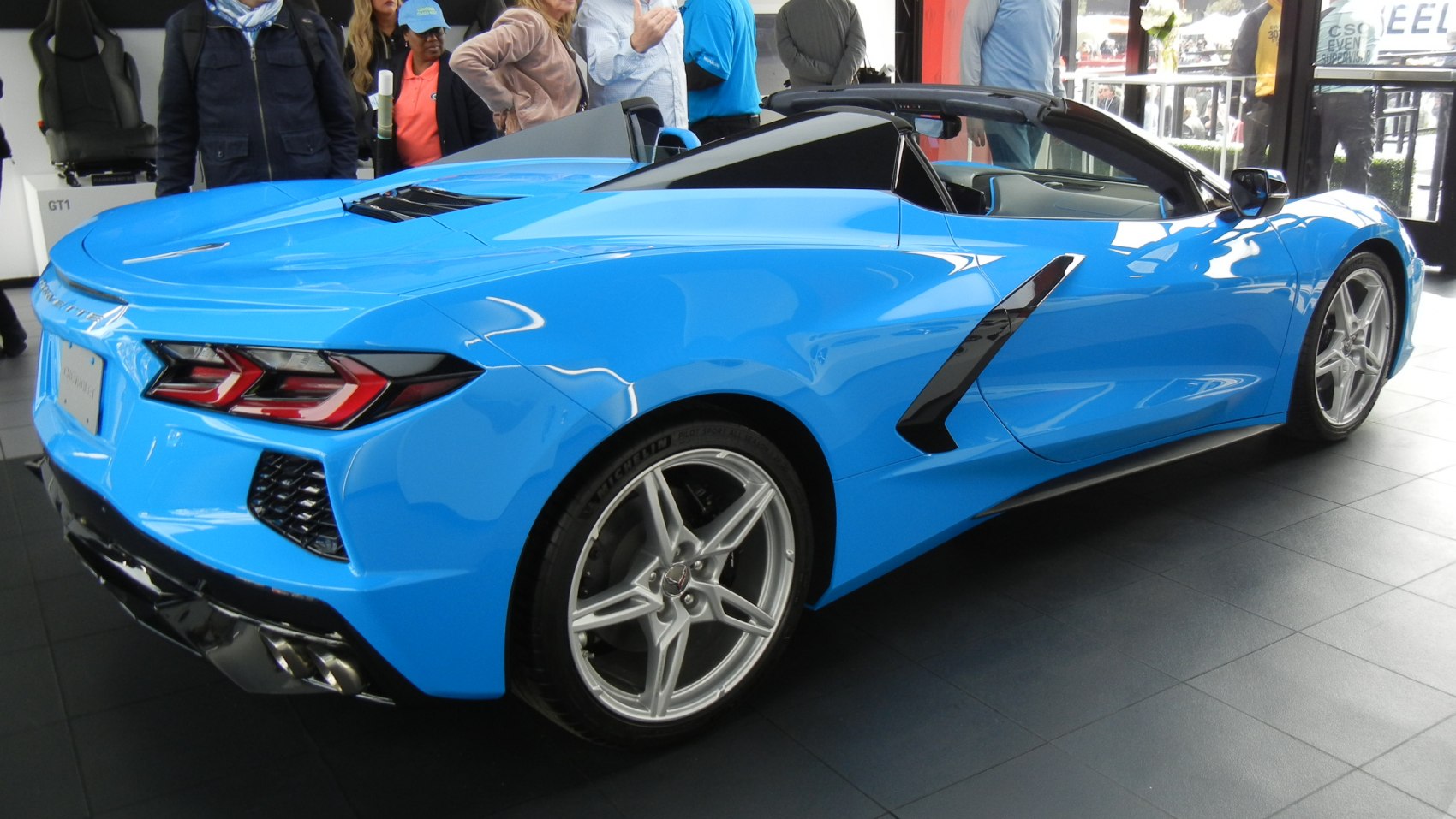 Rear-side view of blue mid-engine convertible with sleek design and distinctive taillights