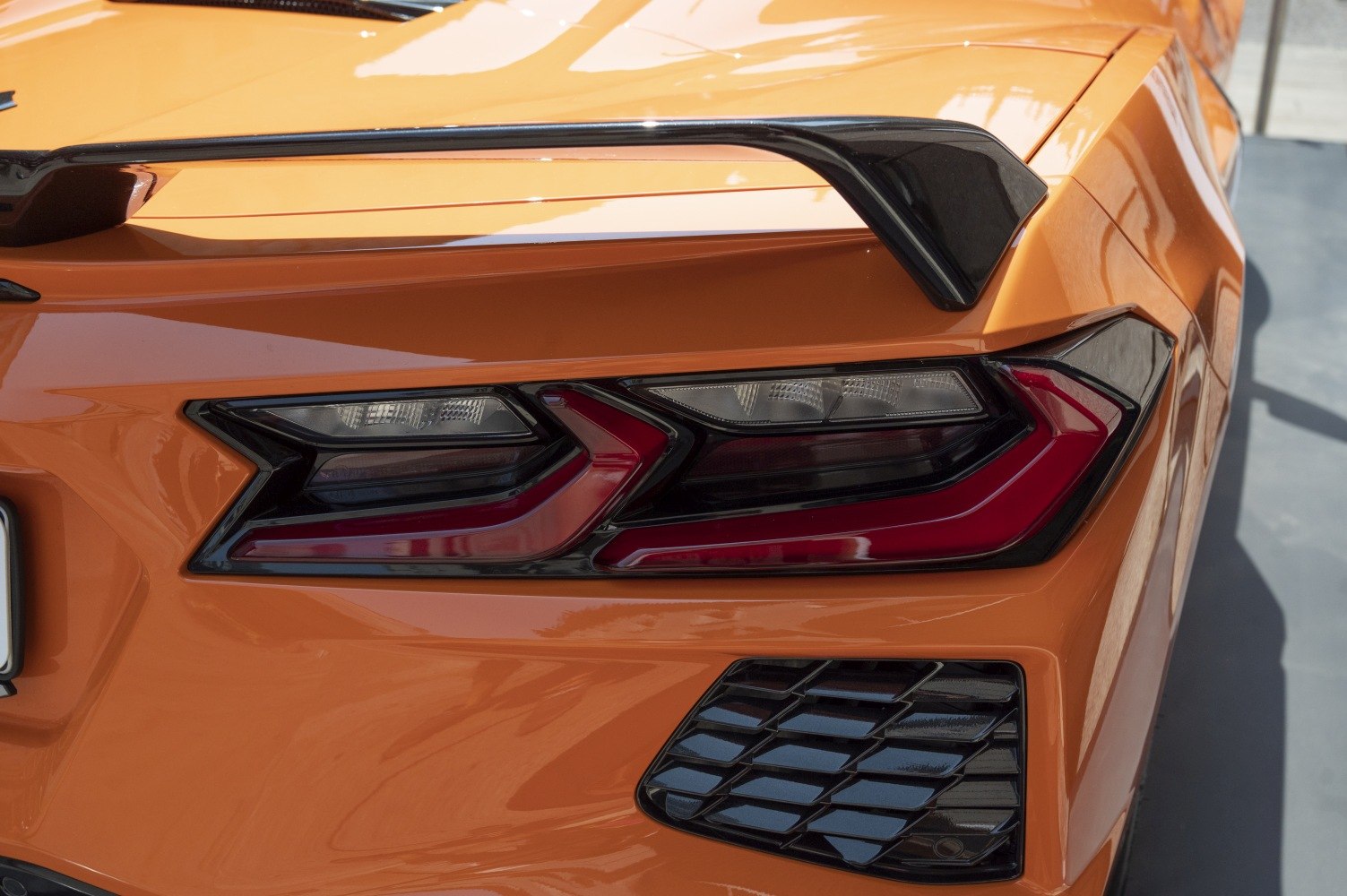 Angular rear tail light and black spoiler on bright orange sports car