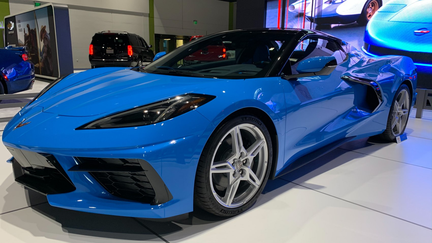 Blue mid-engine sports coupe with angular headlights and aerodynamic front.