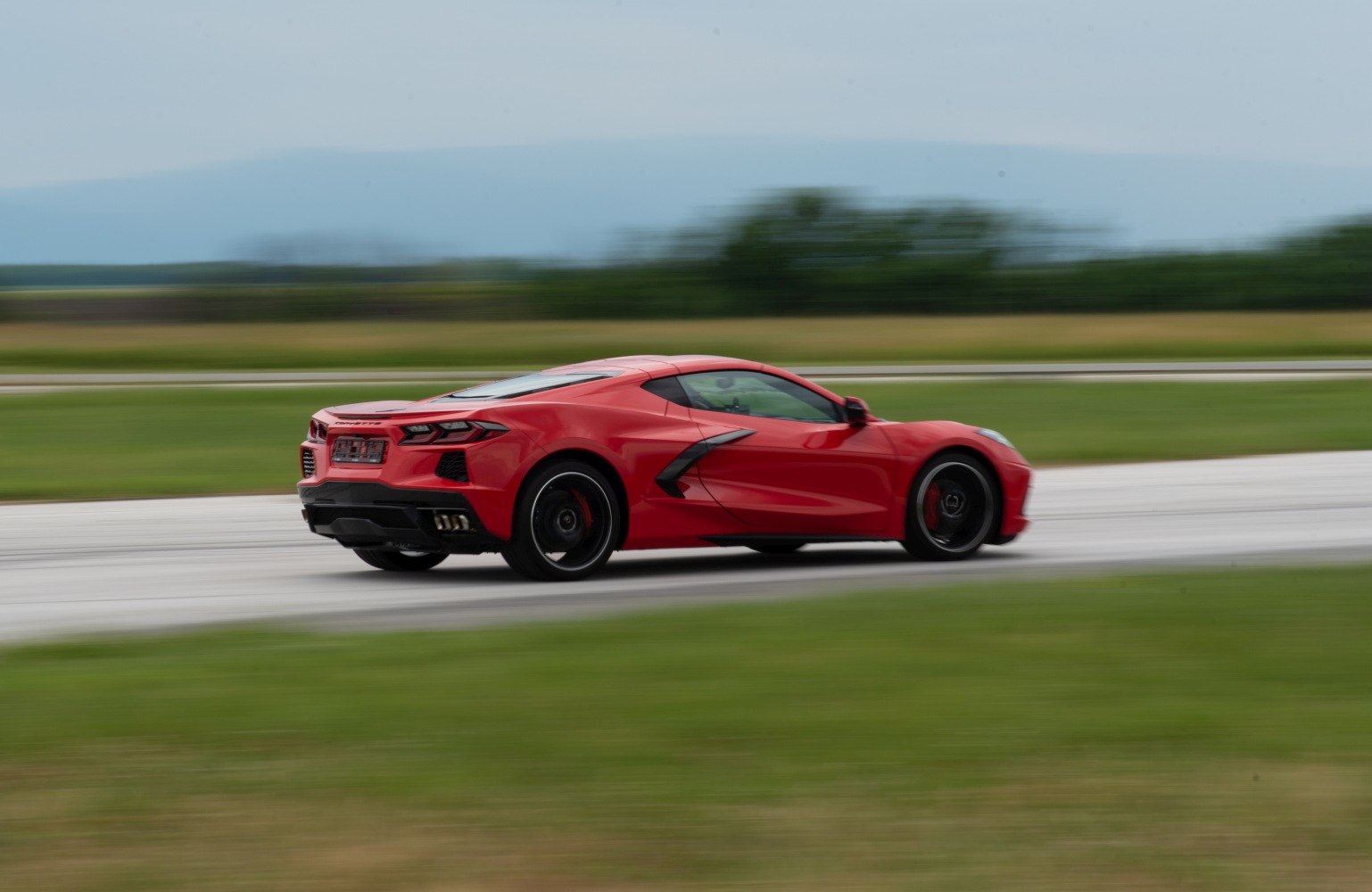 Red sports coupe rear side view in motion