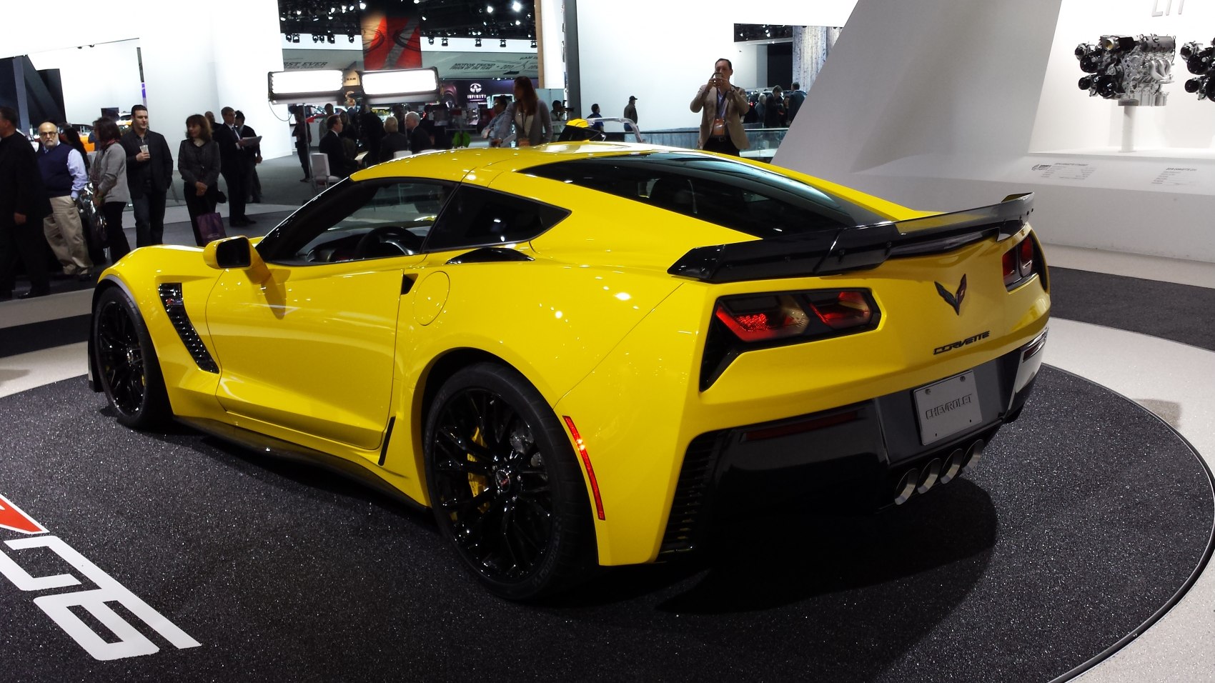 Yellow sports coupe with black wheels, quad exhaust, and rear spoiler