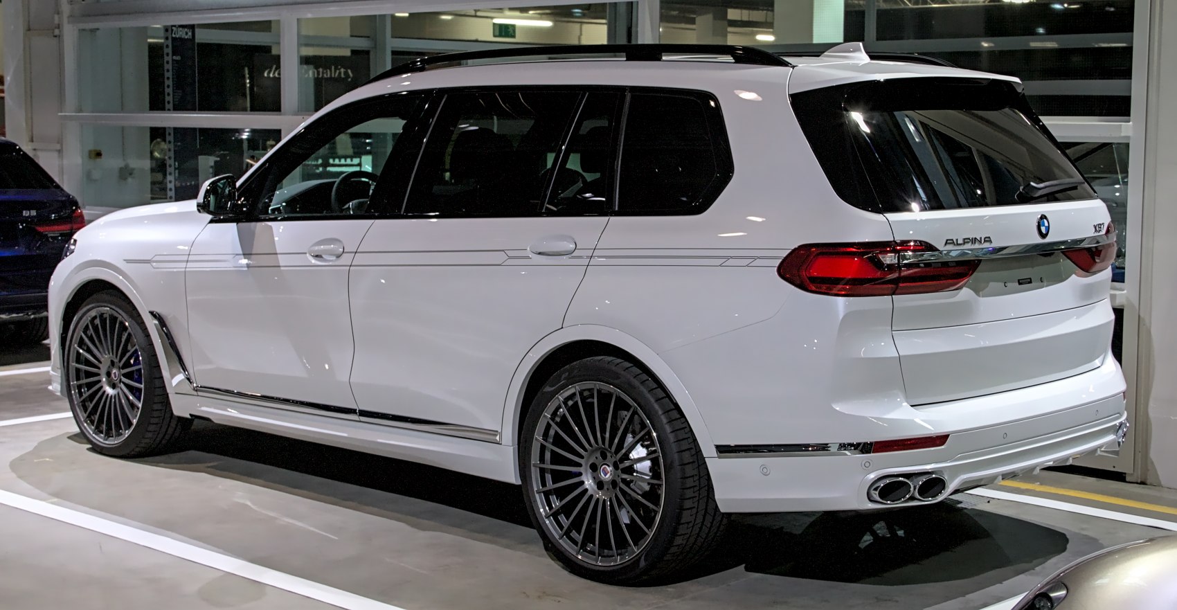 White luxury SUV with quad exhaust pipes and multi-spoke alloy wheels.