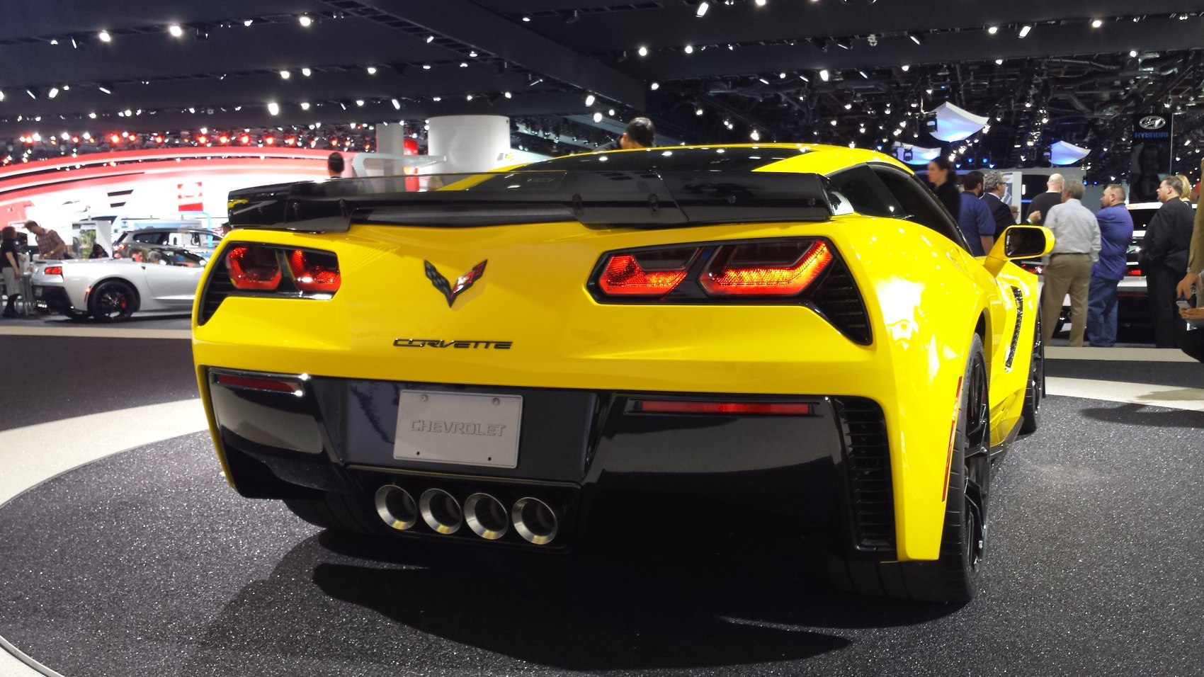 Rear view shows bright yellow coupe with quad exhaust and distinct taillights