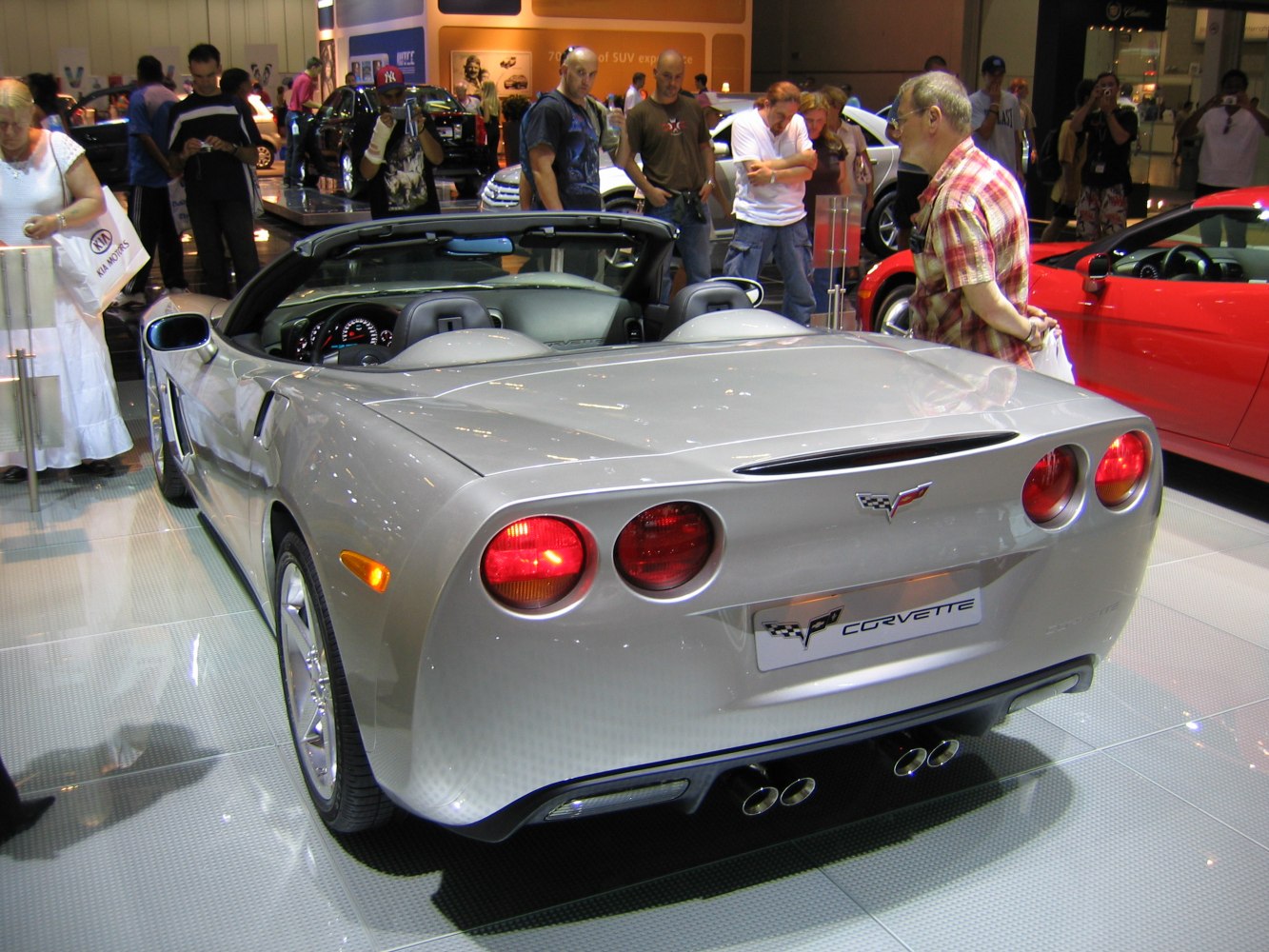 Rear view of a silver convertible with round taillights and quad exhaust pipes