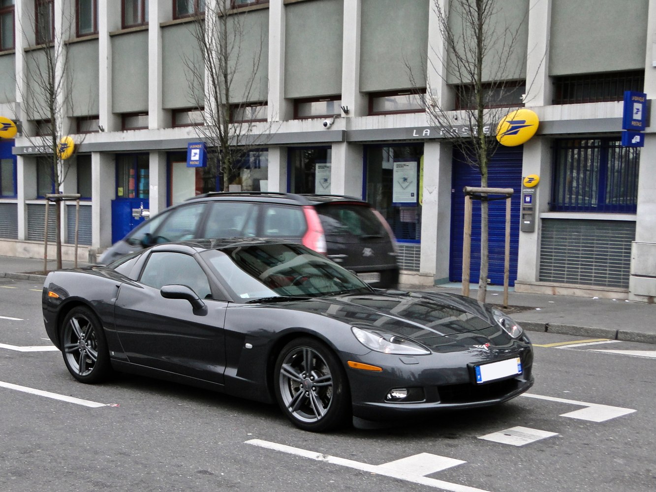 Sleek front-side view of a dark sports coupe on city street.
