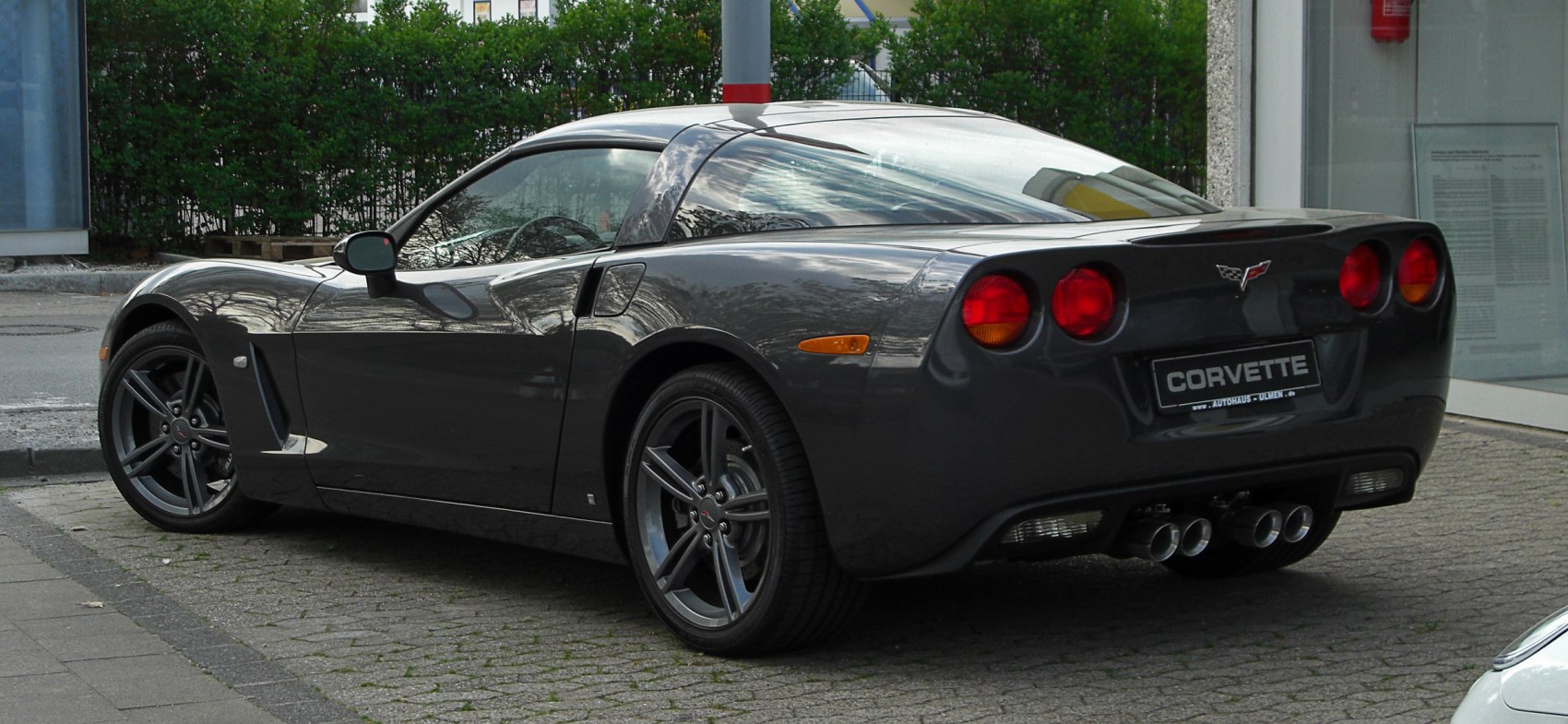 Rear and side view of a black sports coupe with quad exhaust and distinctive taillights