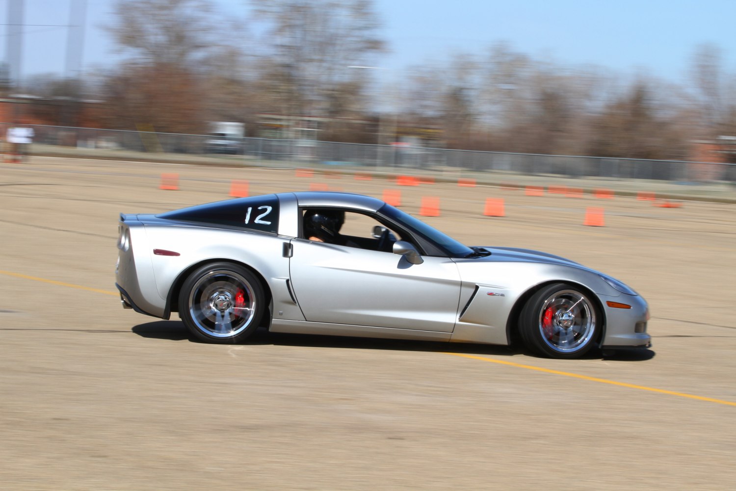 Silver sports coupe with racing wheels in motion on marked track