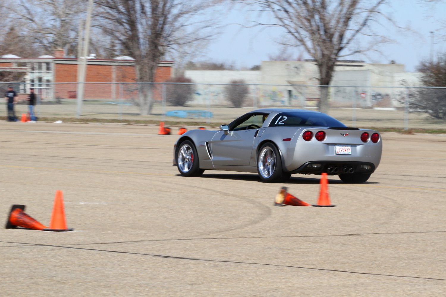 Silver sports coupe navigating an autocross course with cones.