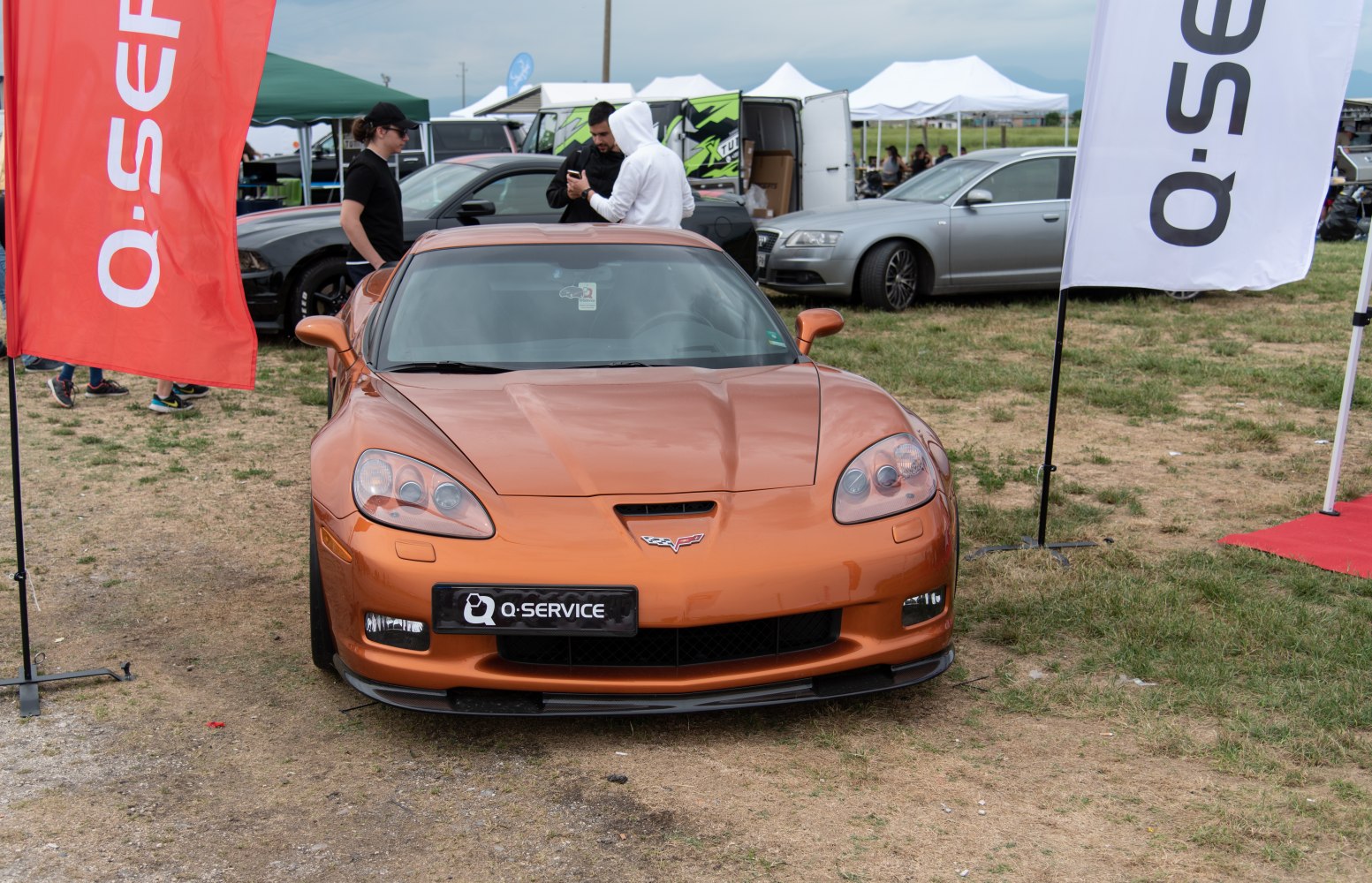 A sporty front view of a metallic orange Corvette C6 with aerodynamic hood and distinct headlights