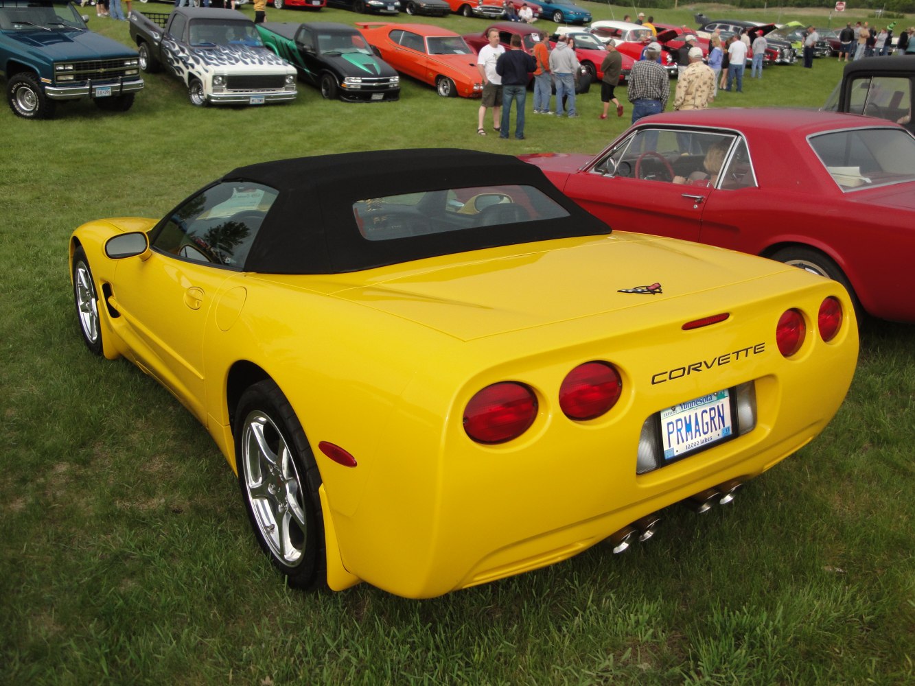 Rear view of yellow Corvette convertible with black soft top and quad round taillights