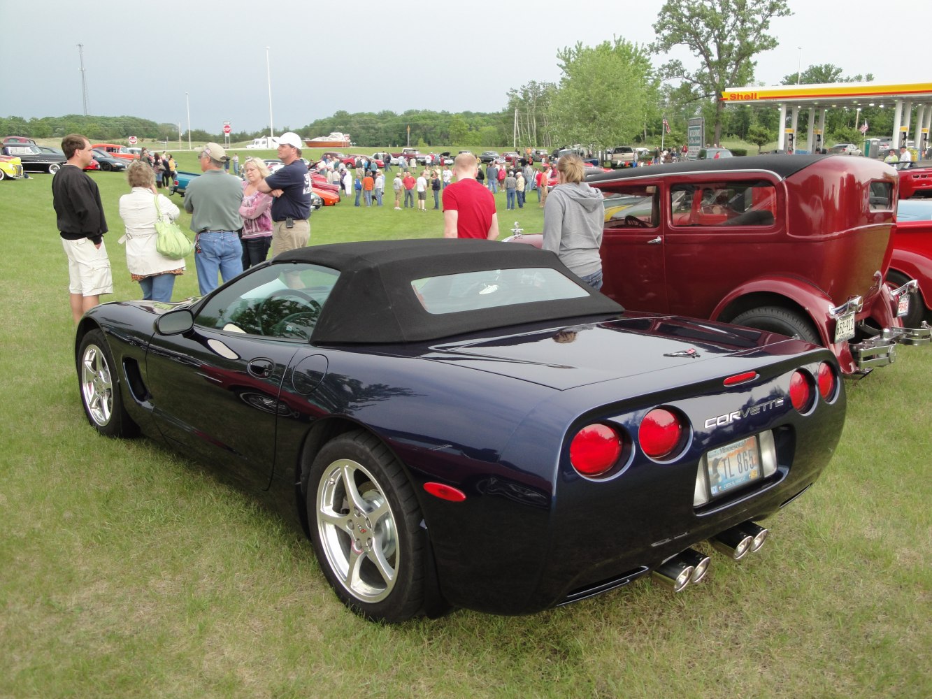Rear view of a convertible with soft top, round taillights, and dual exhaust pipes