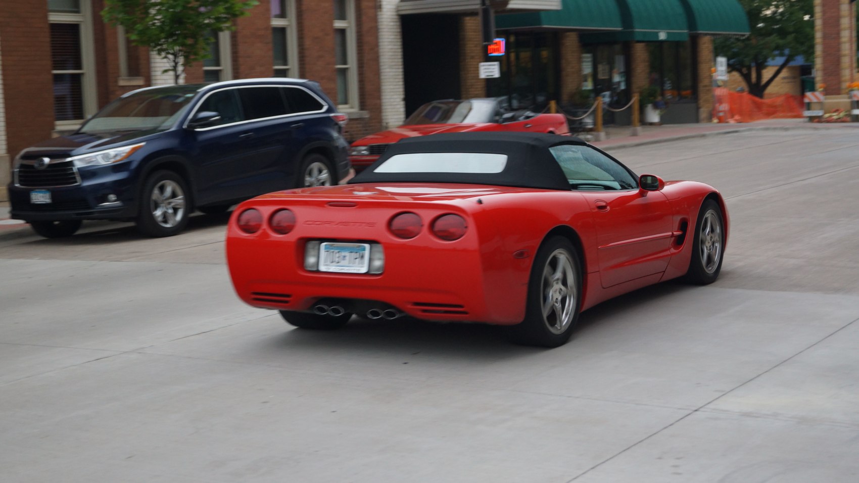 Rear view of red convertible with quad circular taillights and black soft top