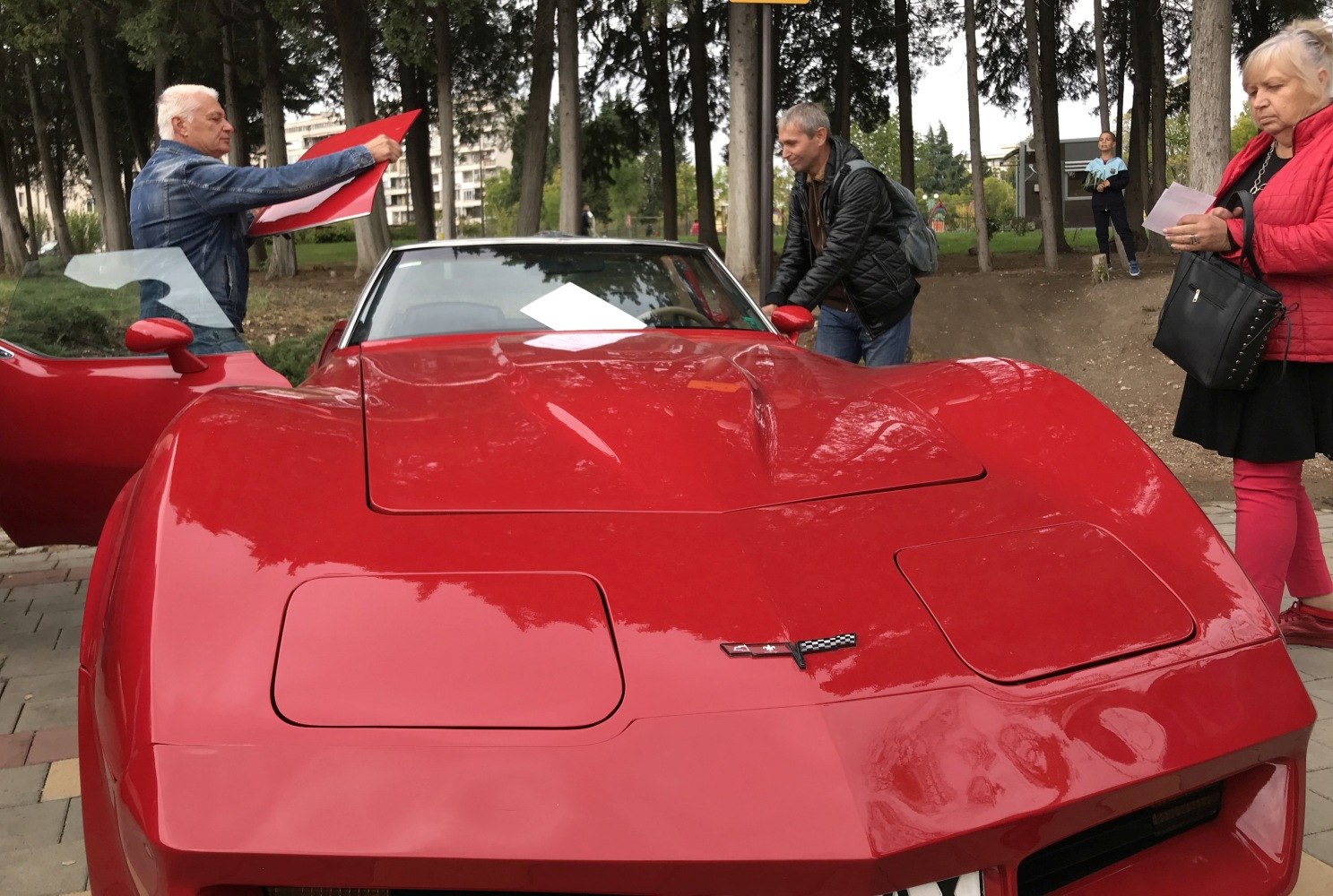Front view of red sports car hood with pop-up headlights and emblem.
