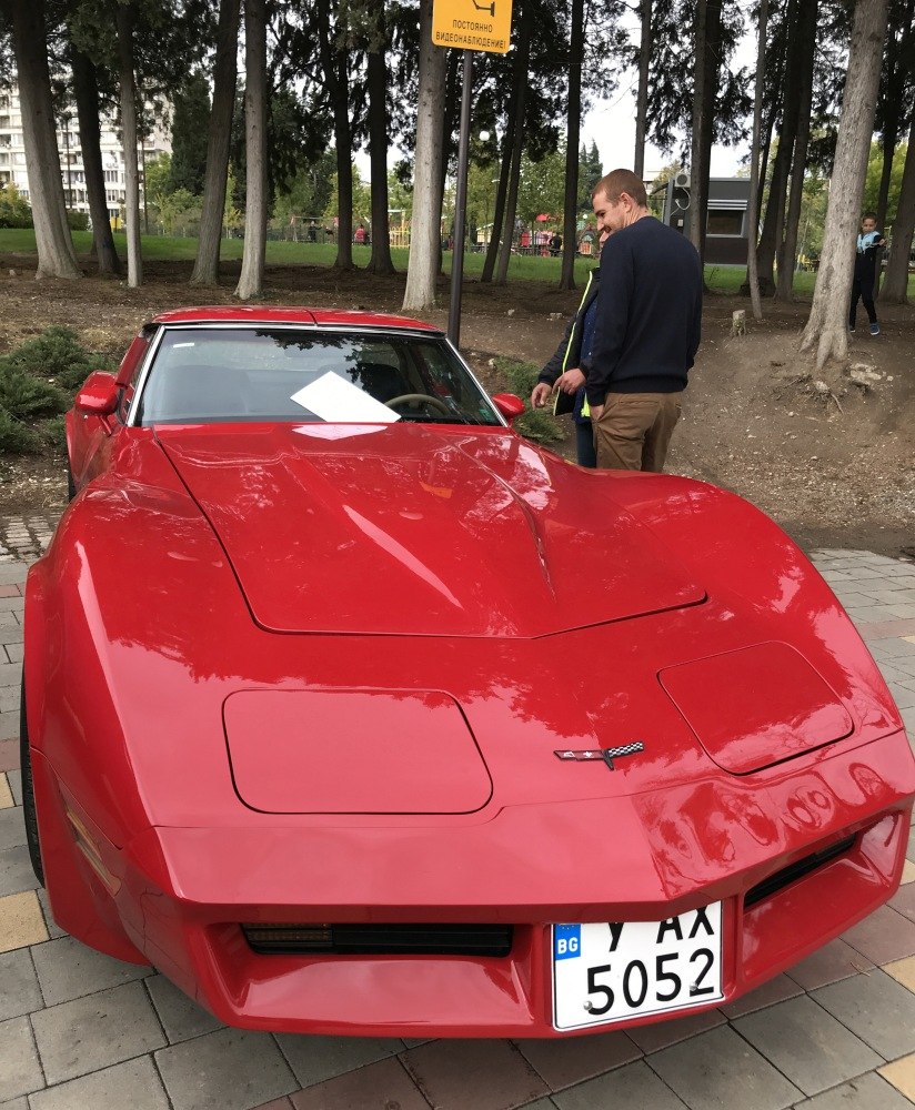 Red classic car front with pop-up headlights and sleek hood lines