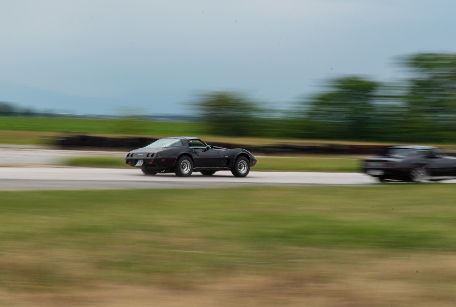 Rear side view of classic Corvette coupe in motion on track