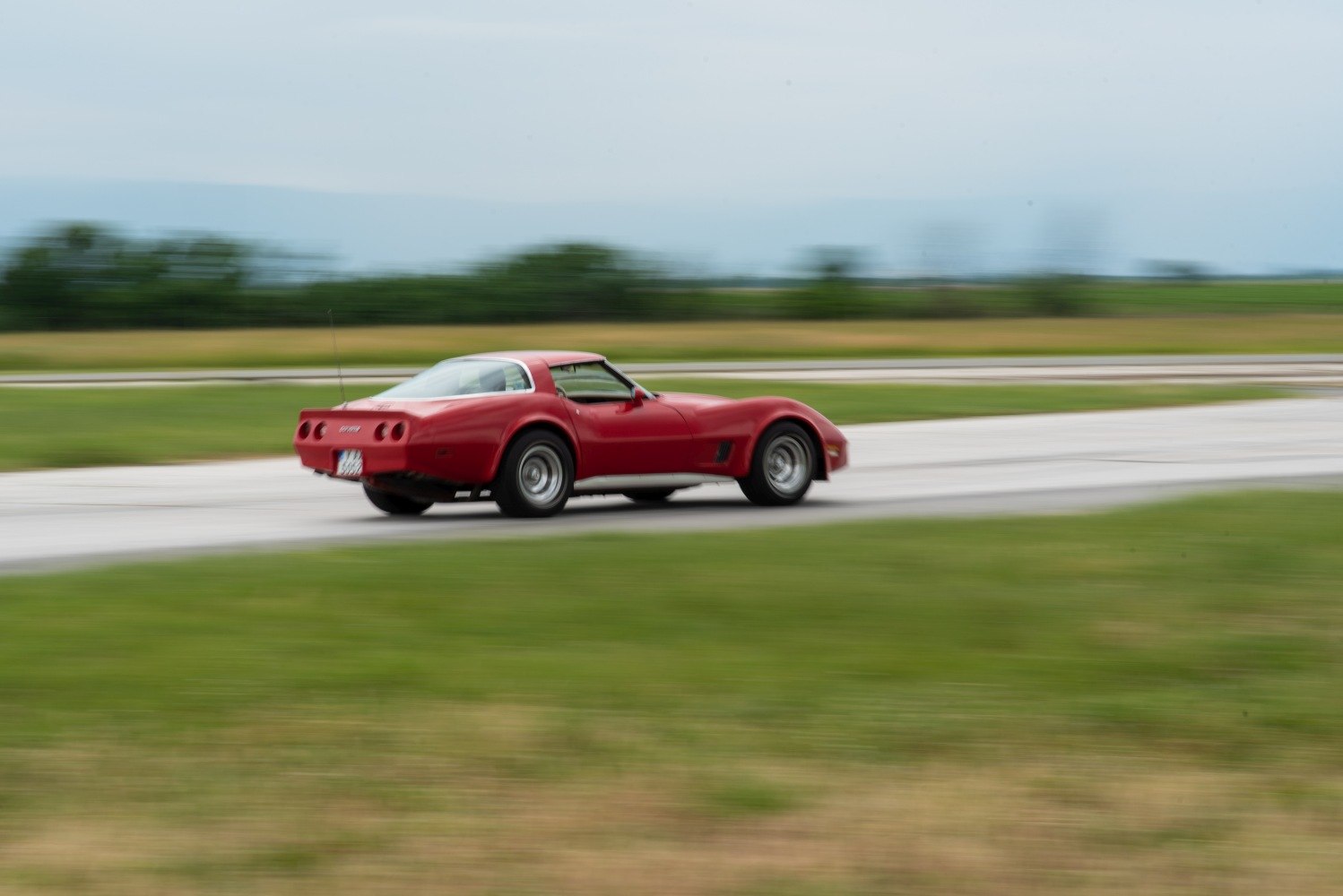 Red classic coupe with distinctive rear and side profile in motion