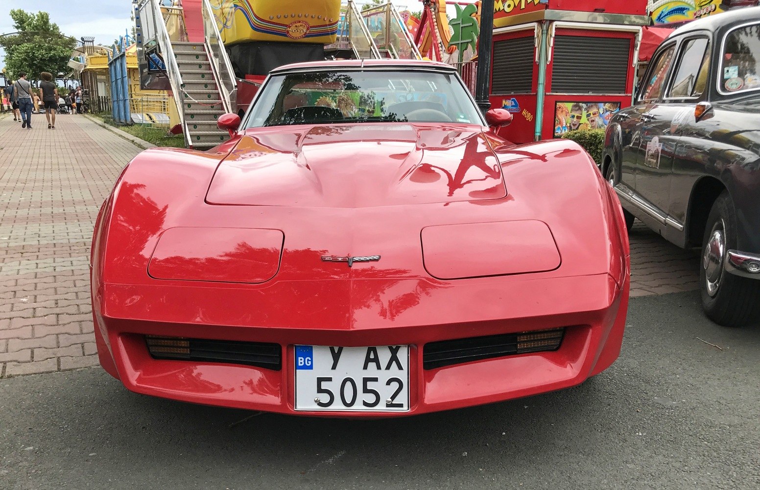 Front view of a red classic muscle car with pop-up headlights and aggressive aerodynamic bonnet.