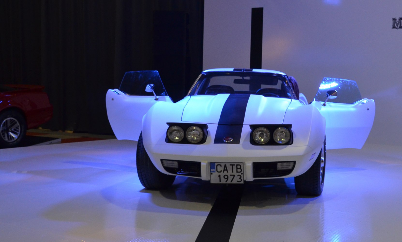 Front view of classic Corvette with open doors and four pop-up headlights