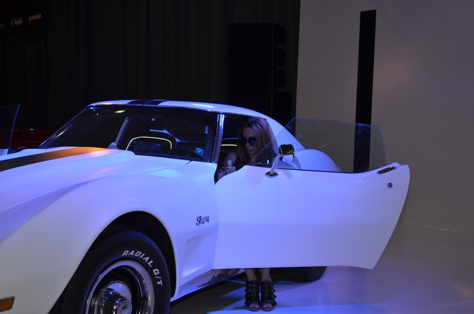 Front door open 1970s muscle coupe with radial tires and woman inside
