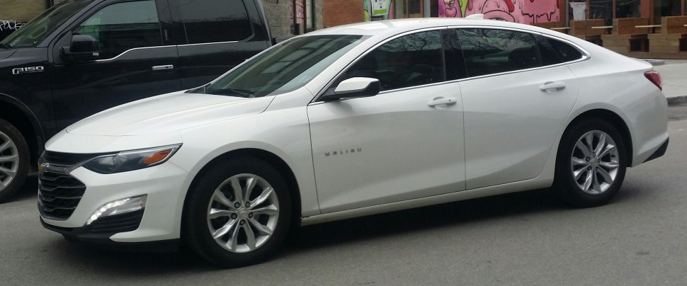 White mid-size sedan with facelift front and alloy wheels side view