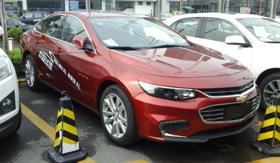 Red sedan front view with LED headlights and chrome grille