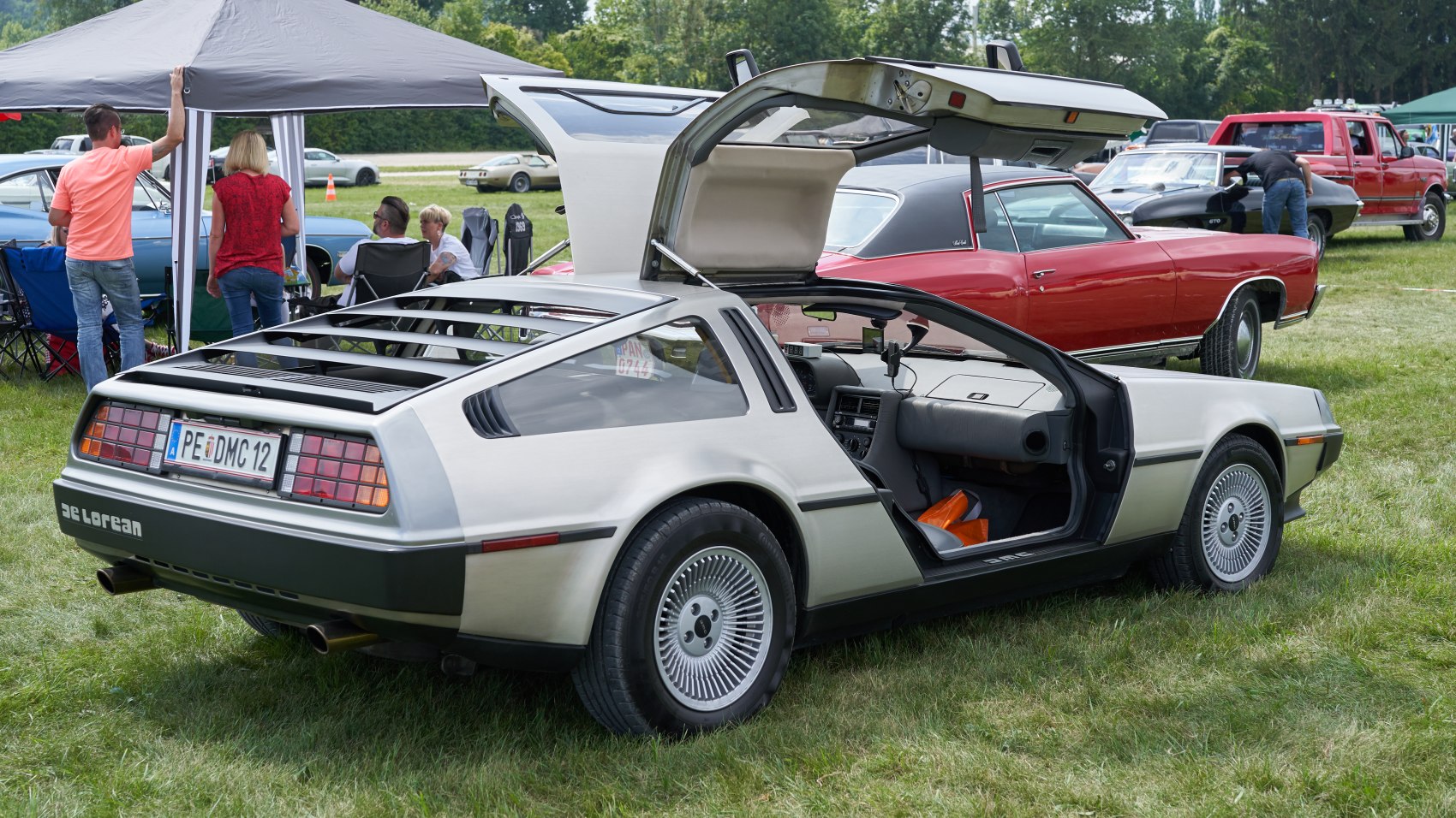 Gullwing door open view with rear louvered window and wide tire.