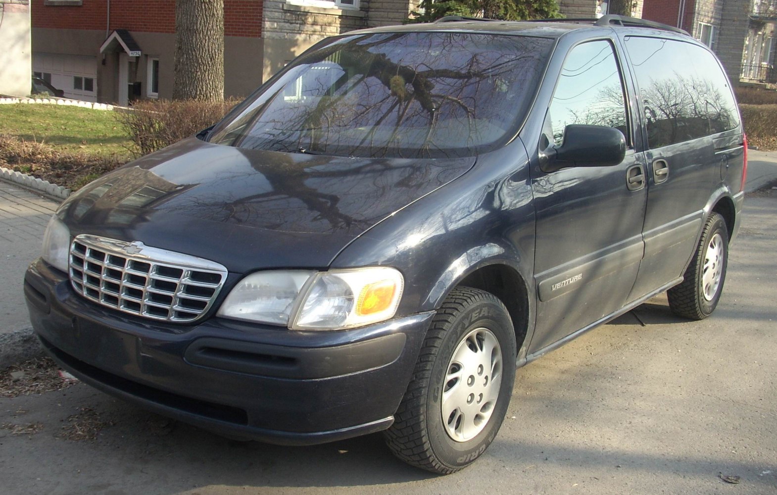 Front side view of a minivan with grille and sliding door