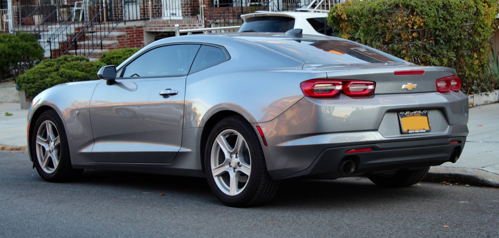 Rear and side profile of a silver modern muscle coupe with distinctive taillights