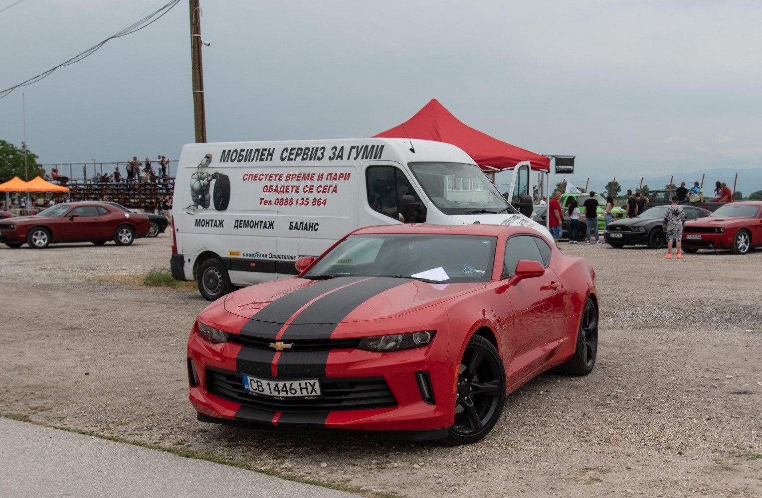 Red coupe with black racing stripes and black wheels front view