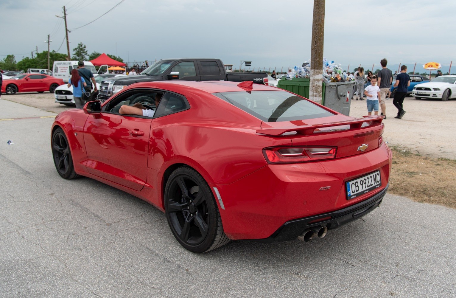 Rear-side view of red sports coupe with black wheels and rear spoiler