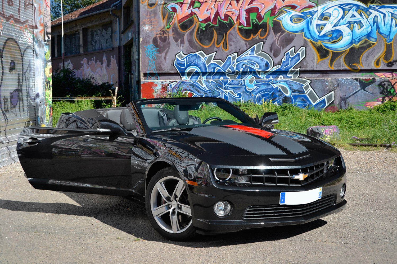 Black convertible with racing stripes, front angle, open driver door