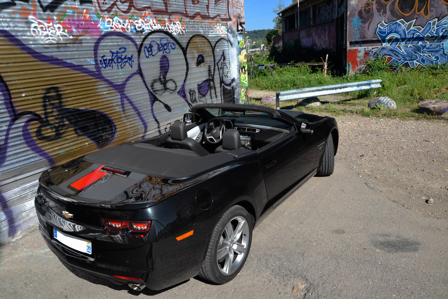 Black convertible with open roof and rear view in urban graffiti setting