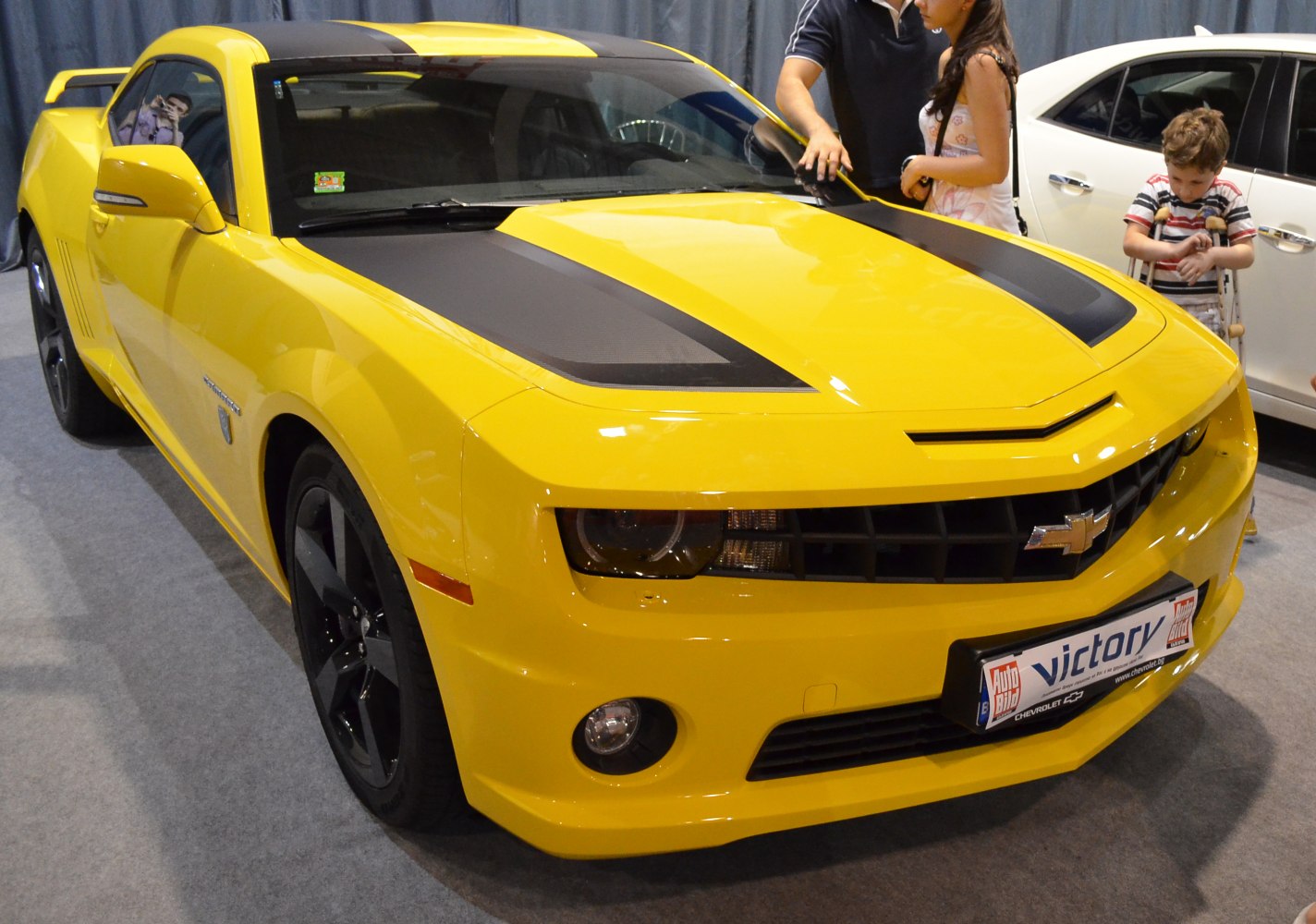 Yellow sports coupe with black racing stripes and aggressive front fascia