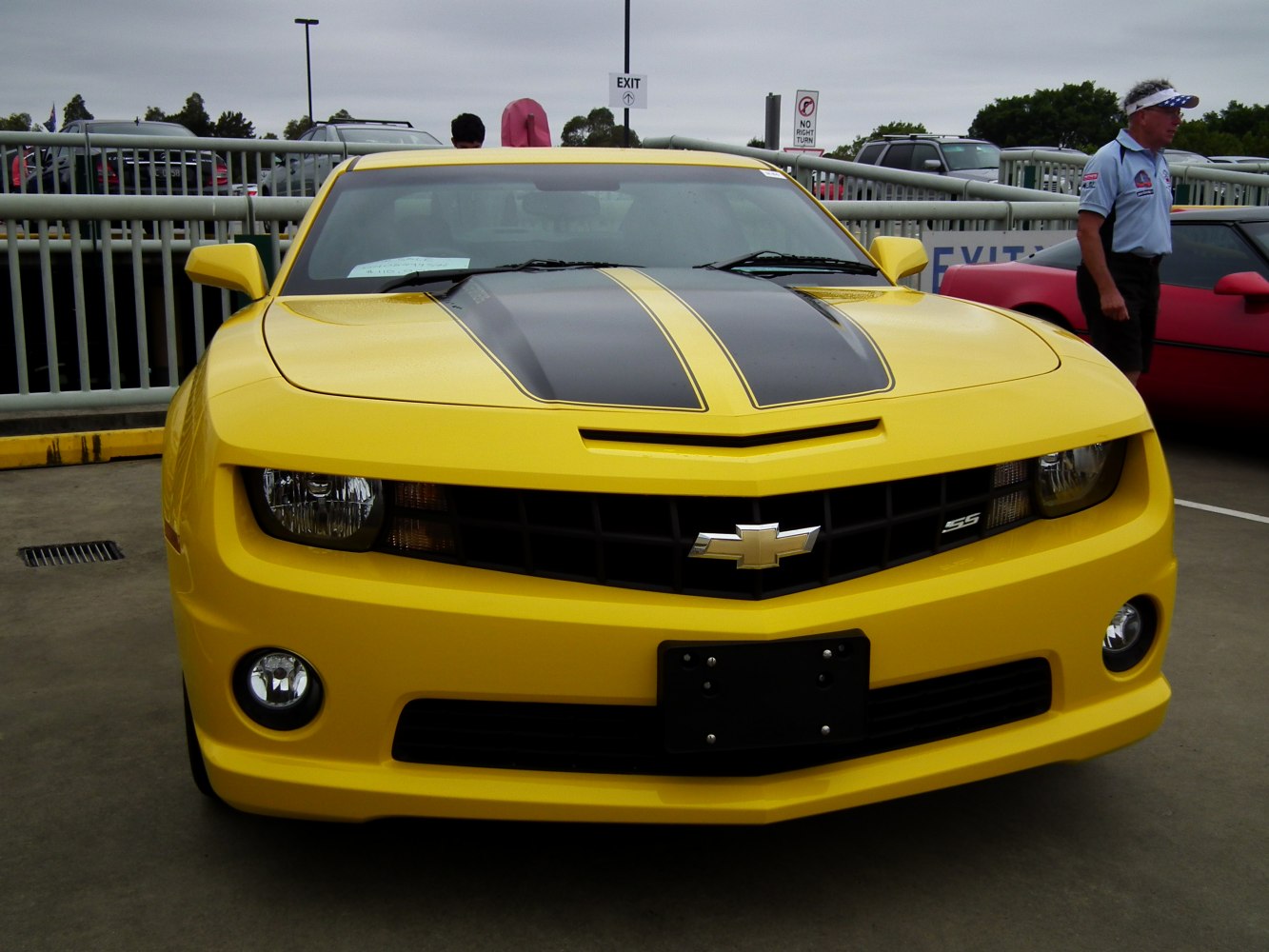 Front view of yellow muscle car with black racing stripes and SS badge