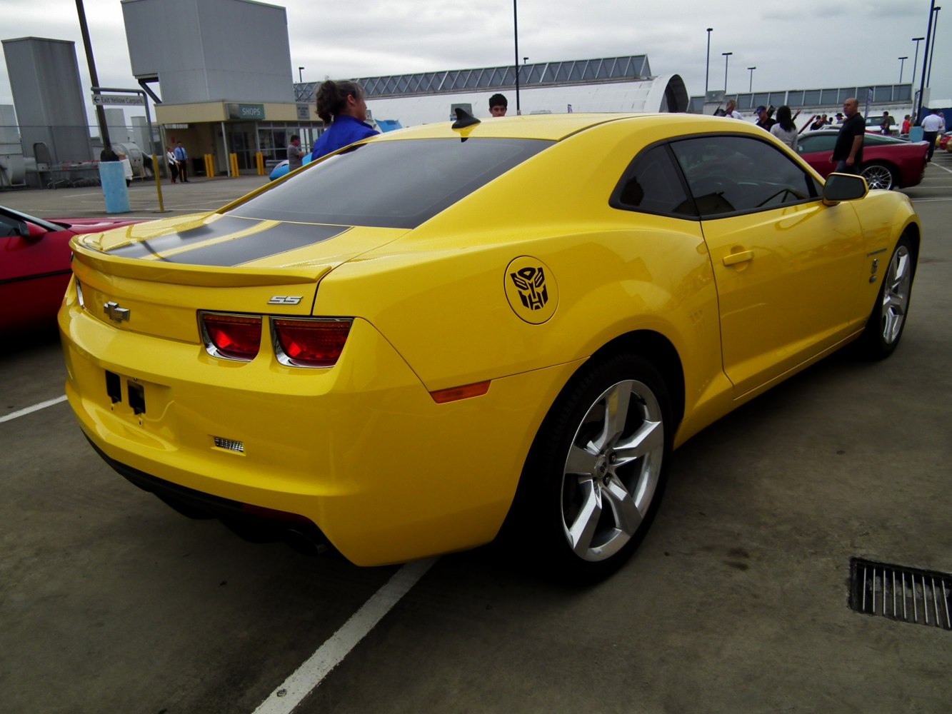 Rear view of yellow muscle coupe with black stripe and Autobot decal
