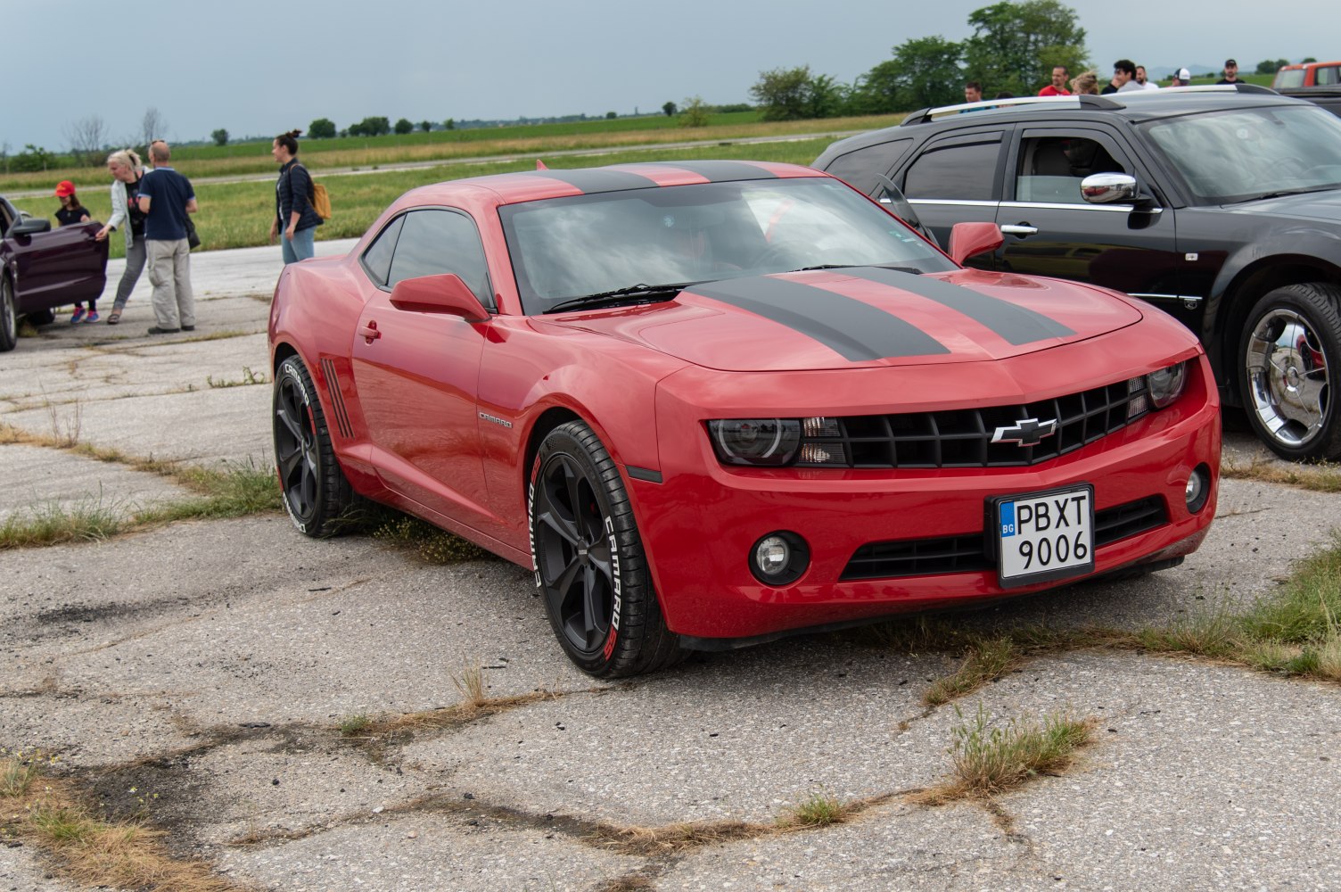 Red muscle car with black racing stripes and black alloy wheels