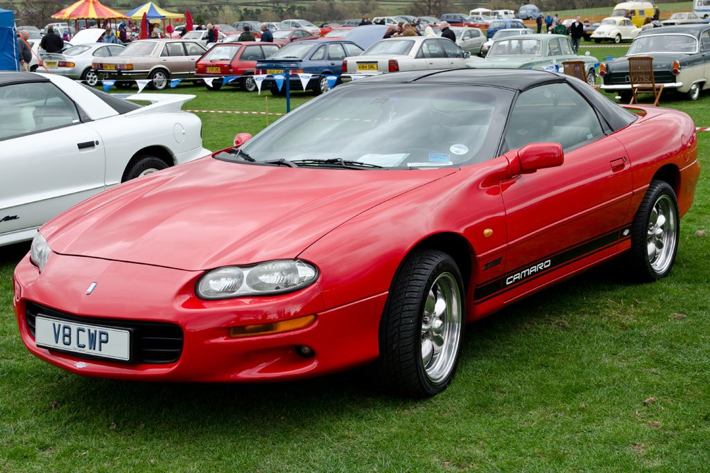 Red sports coupe front angled view with clear headlamps and sporty wheels