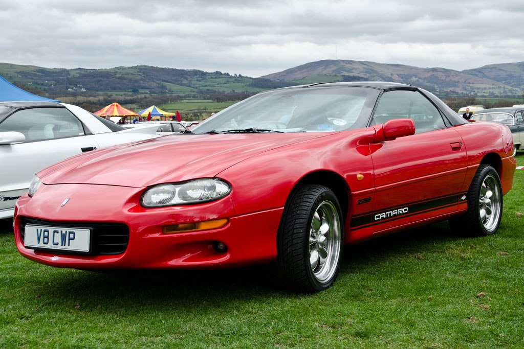 Red coupe with black roof, distinctive front lights, and black side stripe