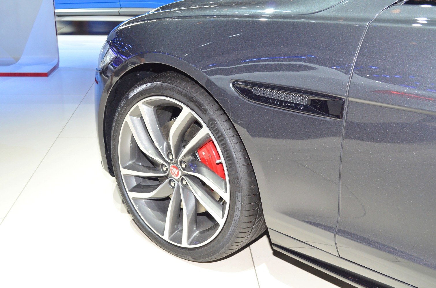 Front wheel with red brake caliper and side vent on grey vehicle